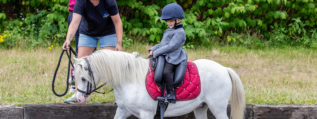 Young child riding a pony with an inky dinky sadle