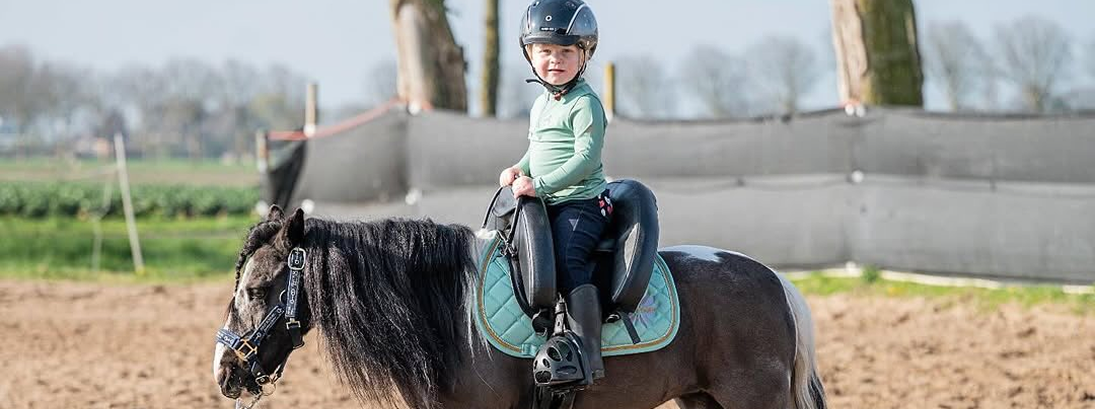 Young child riding a pony using an Inky Dinky treeless saddle, showing secure seat and balanced riding position for beginner riders