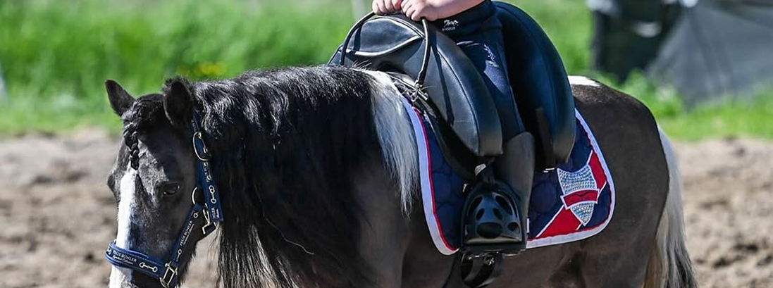 Young child riding a pony using an Inky Dinky childrens pony saddle, showing secure seat and balanced riding position for beginner riders