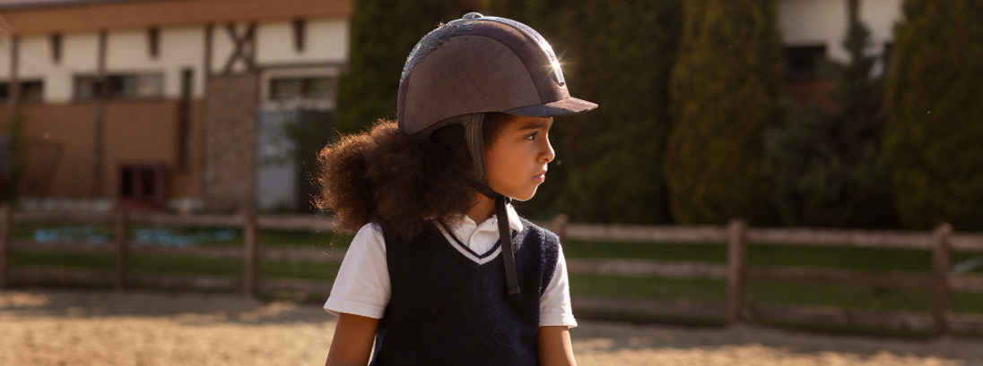 A girl riding a pony wearing a helmet